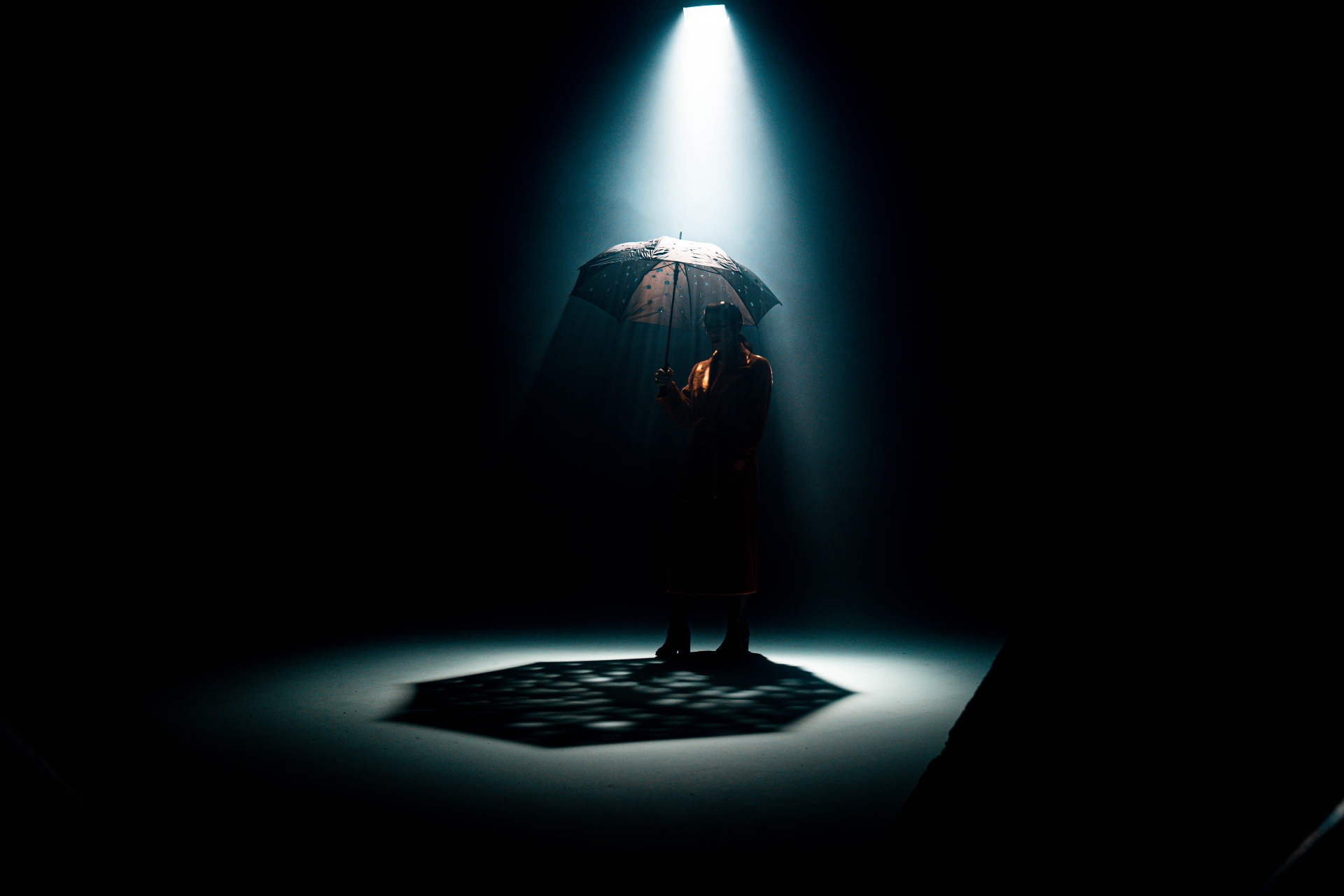Figure under a shaft of light with umbrella