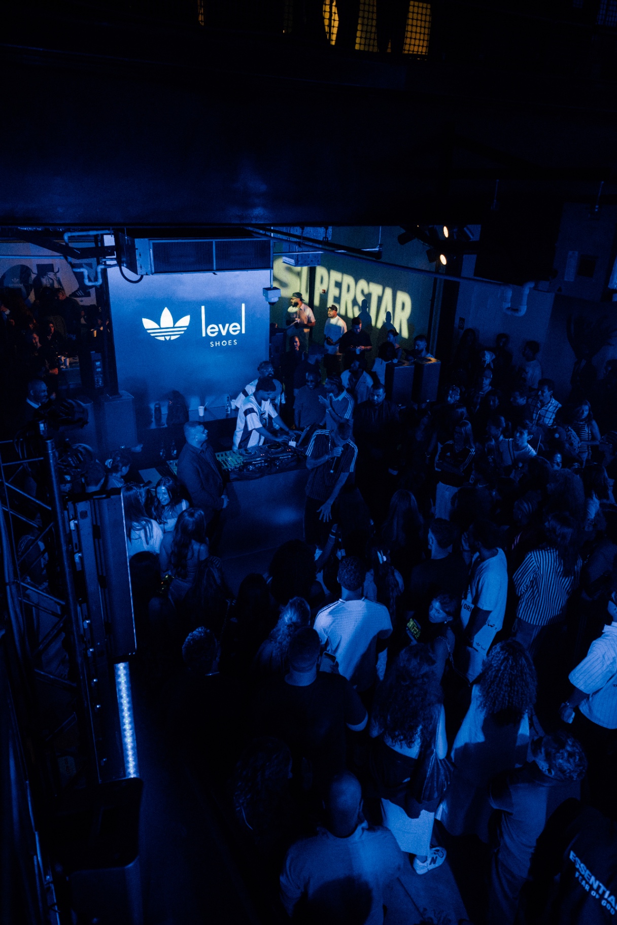 Crowded event space with blue stage lighting and DJ booth